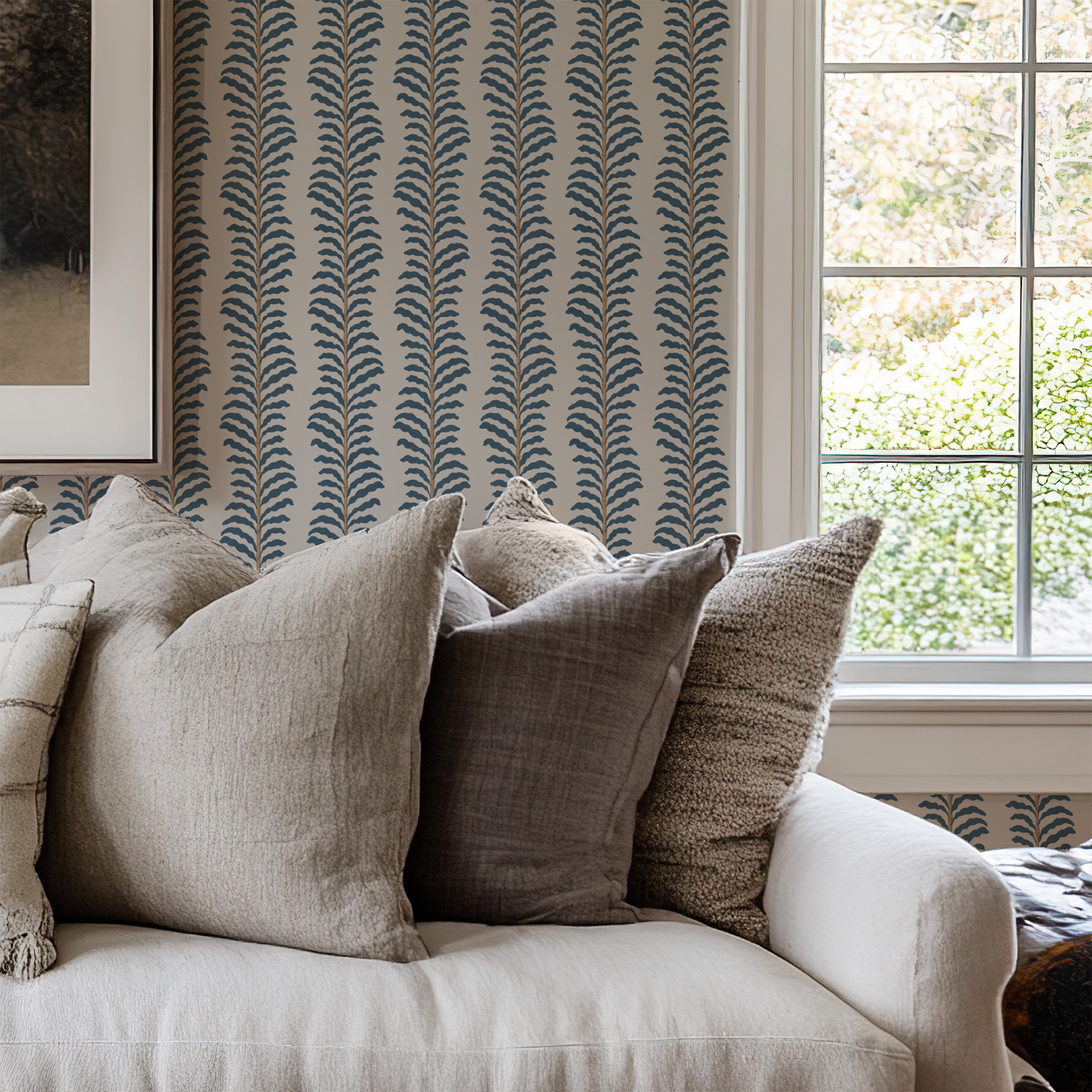 Decorative pillows on a sofa with patterned wallpaper and window in the background